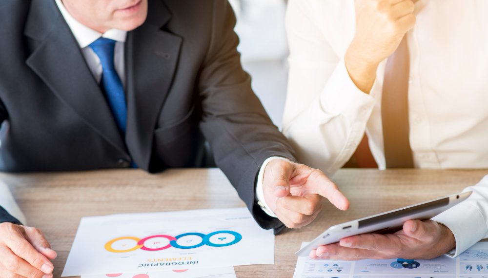 businessman-pointing-finger-digital-tablet-hold-by-his-partner-workplace